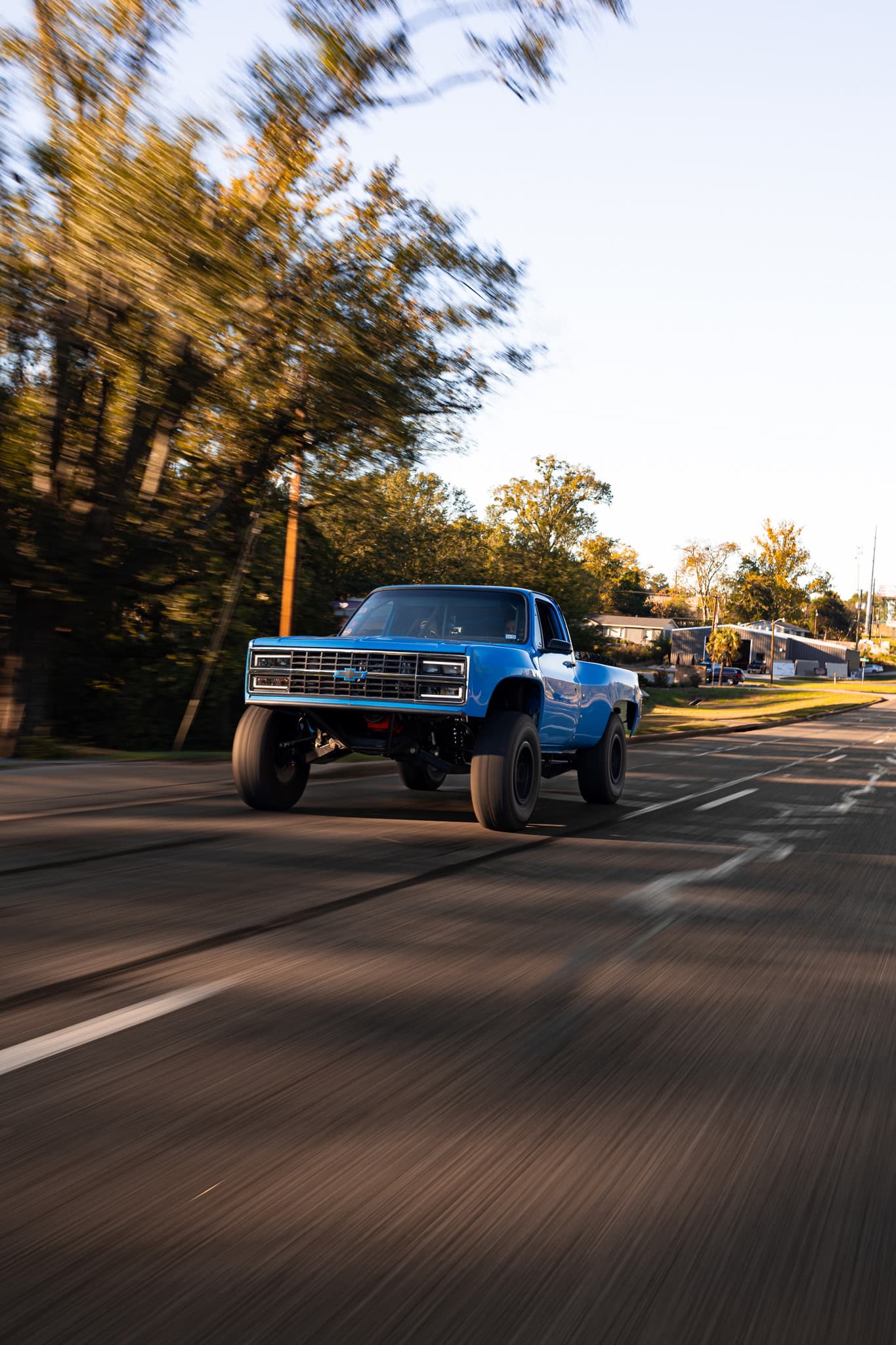 Blue square body Chevy pre-runner truck driving down the road